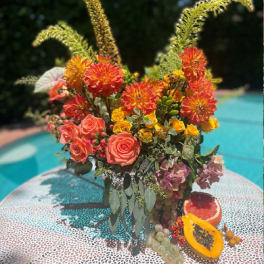 Bright mixed bouquet with orange dahlias and coral roses in a vase