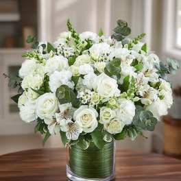 White rose bouquet in a glass vase with green foliage