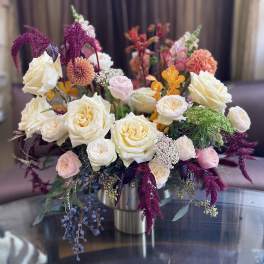 Mixed bouquet of cream, pink, and orange flowers in a metal vase