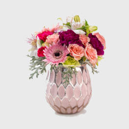 Mixed pink and peach flowers in a pink ceramic vase