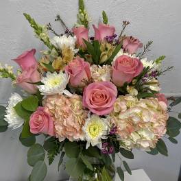 Pink roses and mixed blooms arranged in a clear glass vase