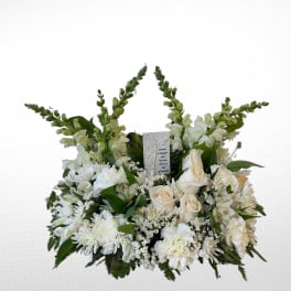 White floral sympathy arrangement with roses and daisies around a memorial card