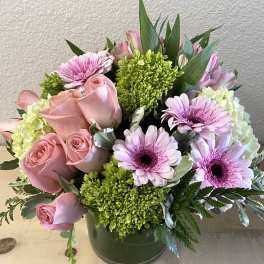 Pink roses and lavender daisies arranged in a green vase