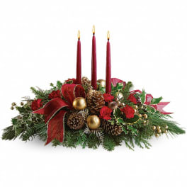 Holiday centerpiece with three red candles, pinecones, and red ribbon