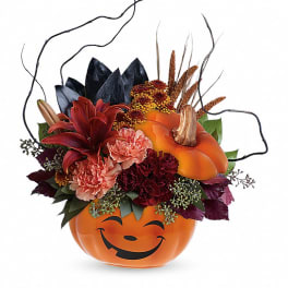 Halloween floral arrangement in a smiling orange pumpkin container
