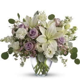 White lilies and lavender roses in a clear glass vase