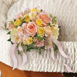 Pink and yellow rose bouquet with ribbon on a white satin cushion