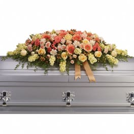 Pastel floral spray arranged on a silver casket