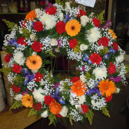 Large multicolored floral wreath on a stand with gerbera daisies and roses
