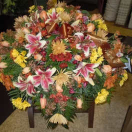 Large casket spray with pink lilies, roses, and yellow flowers