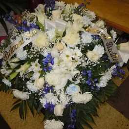 Large white and blue funeral wreath with ribbon banners