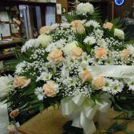 Large white and peach floral arrangement with a ribbon banner