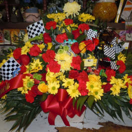 Large red and yellow floral arrangement with checkered flags and toy cars