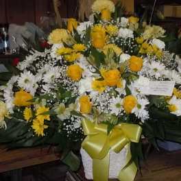 Yellow roses and white daisies in a white basket with a yellow ribbon