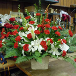 Large red and white floral arrangement in a textured vase
