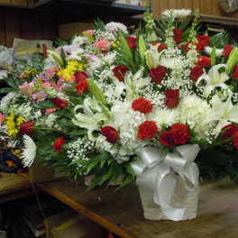 Large mixed floral arrangement in a white vase with a ribbon bow