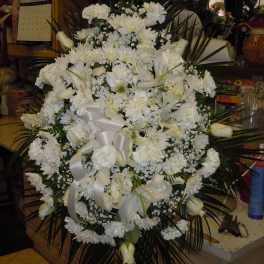 Large white funeral spray with lilies, daisies, and ribbon