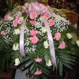 Pink and white floral casket spray with ribbon bows