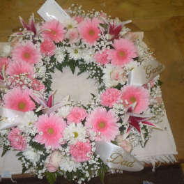 Pink and white funeral wreath with ribbon labels for family members