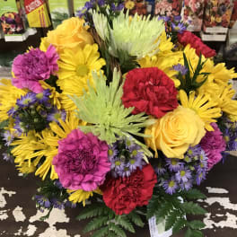 Colorful bouquet of roses, carnations, and daisies in bright yellow, pink, red, and purple