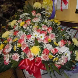 Large mixed bouquet of roses, daisies, and chrysanthemums with a red ribbon