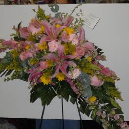 Pink lilies and yellow flowers arranged on a standing spray easel