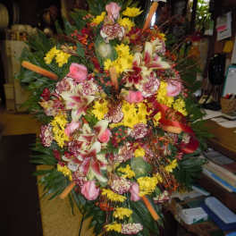 Large standing floral spray with pink lilies, roses, and yellow daisies