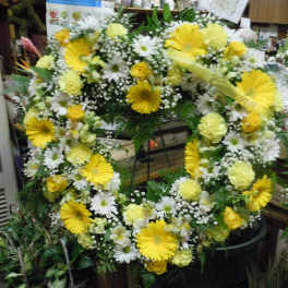 Large yellow and white floral wreath on a stand