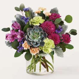 Mixed bouquet with a succulent in a clear glass vase