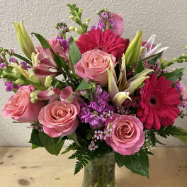 Pink roses and hot pink gerbera daisies in a clear glass vase