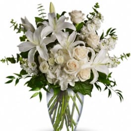 White lilies and roses arranged in a clear glass vase