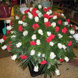 Large funeral spray of white roses and red carnations on a stand
