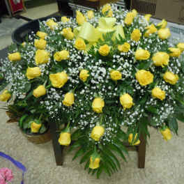 Large yellow rose arrangement with baby's breath in a low container