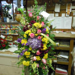 Tall mixed flower arrangement with pink roses, yellow daisies, and purple hydrangea