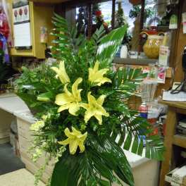 Tall arrangement of yellow lilies and tropical greenery