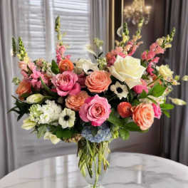 Mixed pink and peach flowers arranged in a clear glass vase