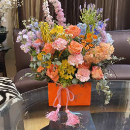 Colorful mixed bouquet in an orange box with pink ribbon tassels