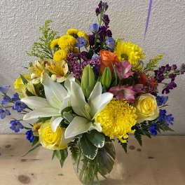 Mixed bouquet of lilies, roses, and bright flowers in a glass vase