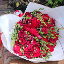 Bouquet of red roses wrapped in white paper with a red ribbon