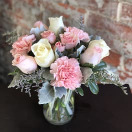 Pink and white roses with carnations in a glass vase