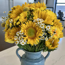 Bouquet of yellow sunflowers and white daisies in a blue ceramic vase