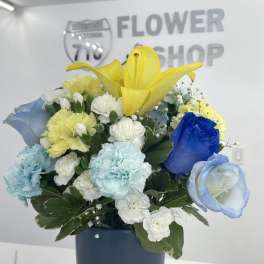 Colorful bouquet with yellow lilies, blue roses, and carnations in a blue vase