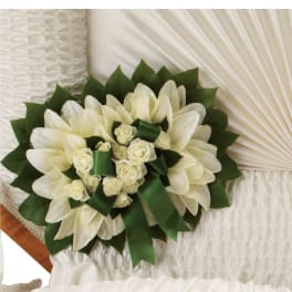 White lilies and roses with green ribbon arranged on a white casket interior