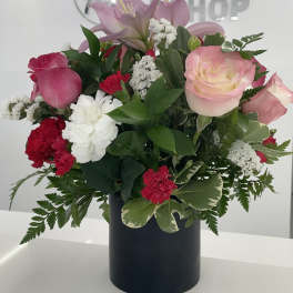 Pink lilies and roses arranged in a black vase