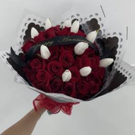 Bouquet of red roses and white tulips wrapped in black and white paper