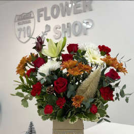 Mixed bouquet of red roses, white lilies, and orange mums in a box vase
