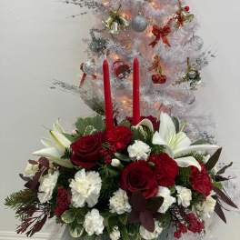 Christmas floral arrangement with red roses, white lilies, and red candles