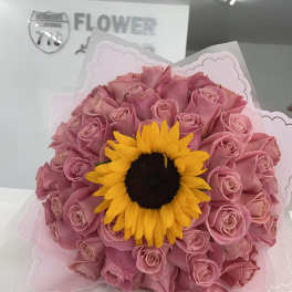 Pink rose bouquet with a sunflower center wrapped in pale pink paper