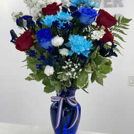 Red and blue roses with white and blue flowers in a cobalt vase