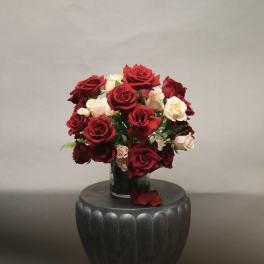 Red and blush roses arranged in a clear glass vase